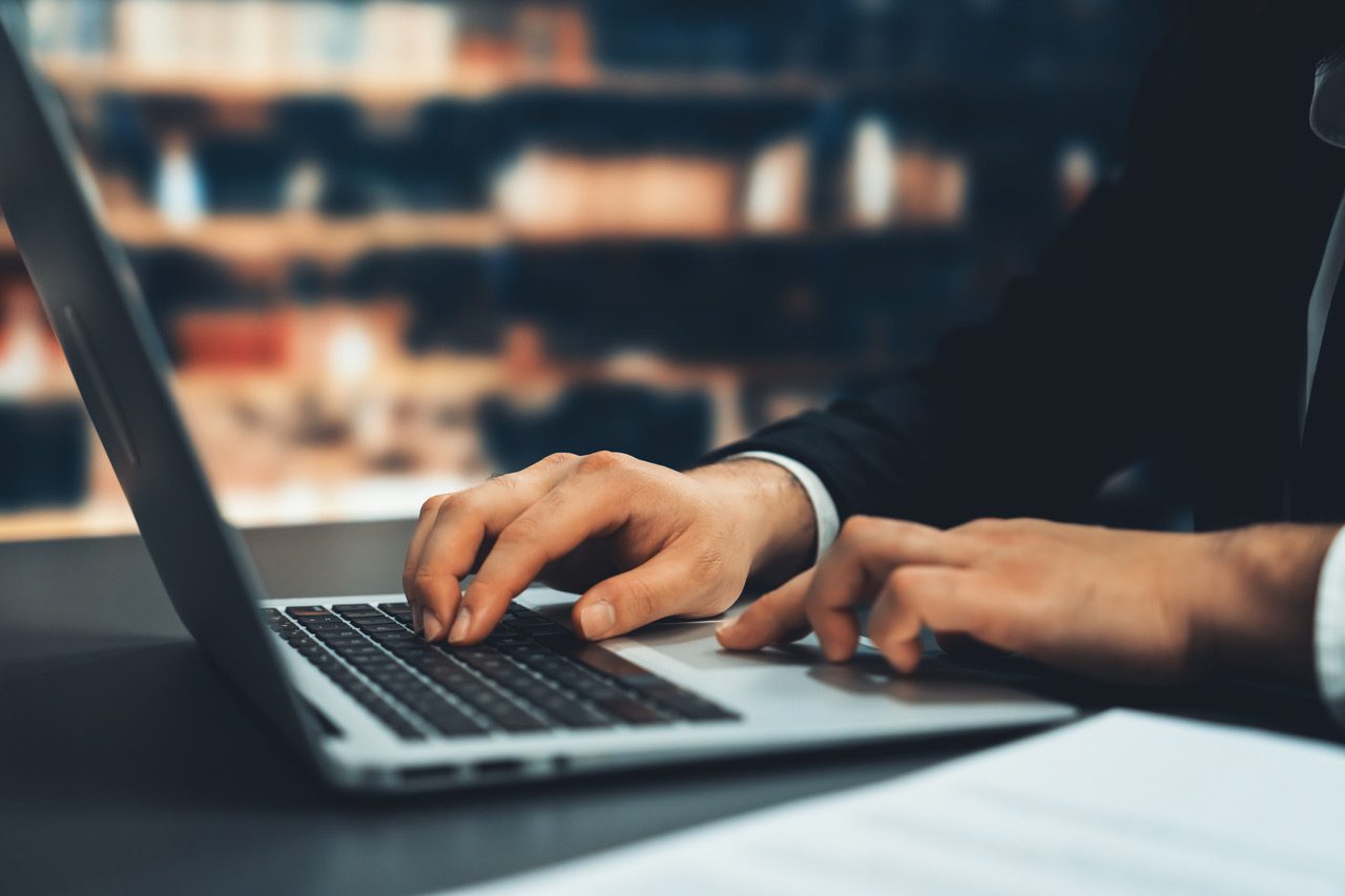 Close-up of a lawyer working with his laptop in a library.